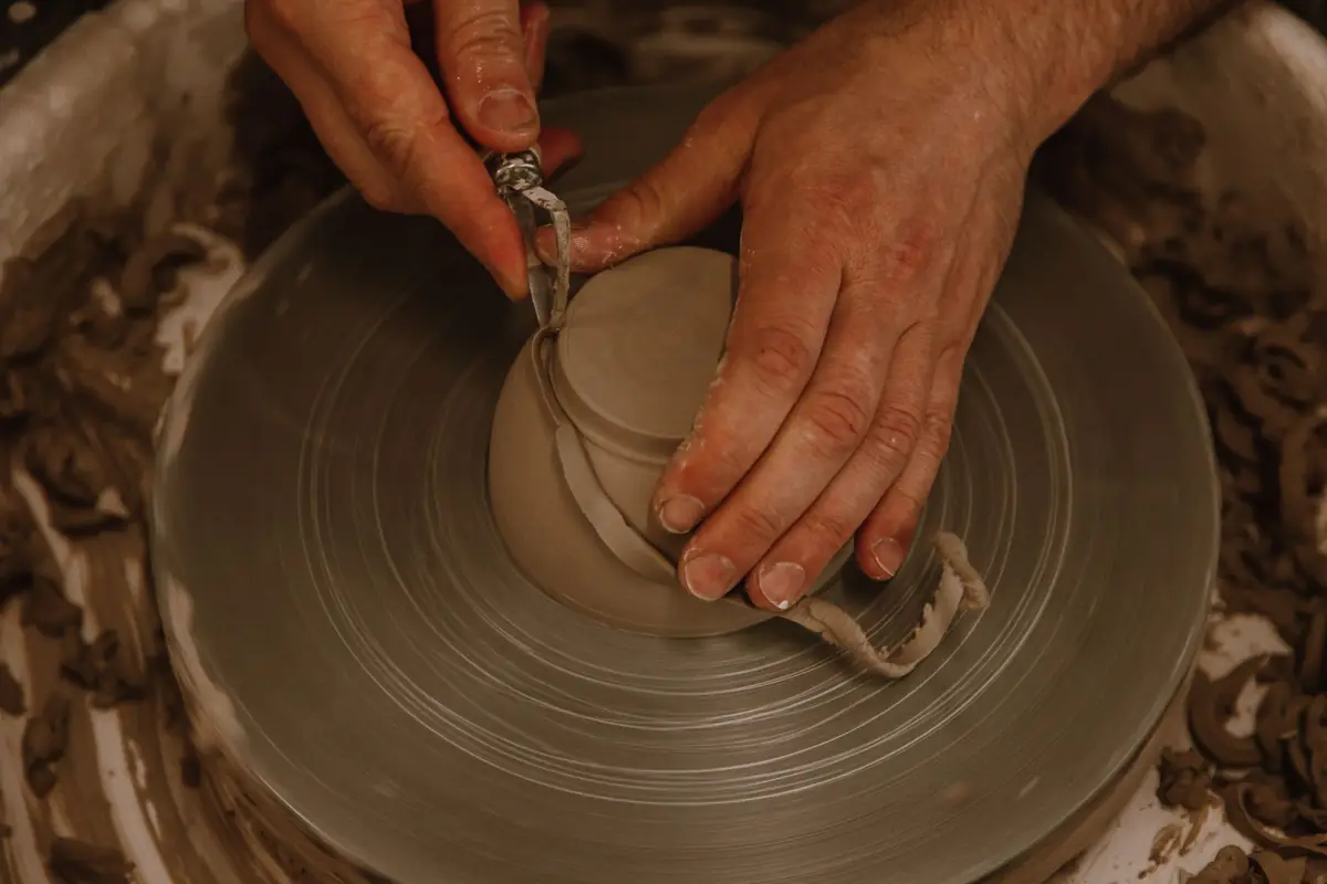 Clay tools and wet hands working at a pottery wheel